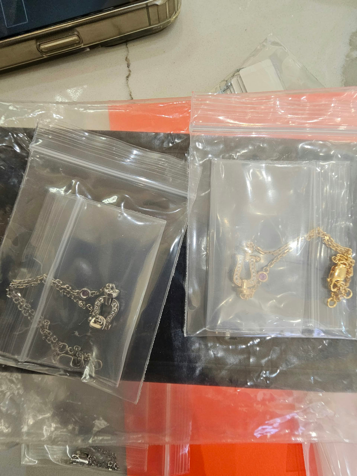 Original reference photo showing White Gold and Yellow Gold Slim Shackle Chain Bracelets with red station stones and white pavé shackle accents.